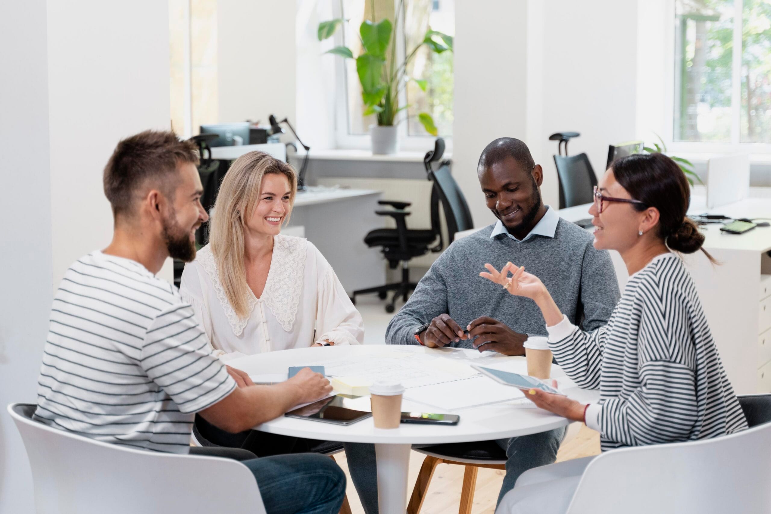 Profissionais reunidos em uma mesa conversando e sorrindo